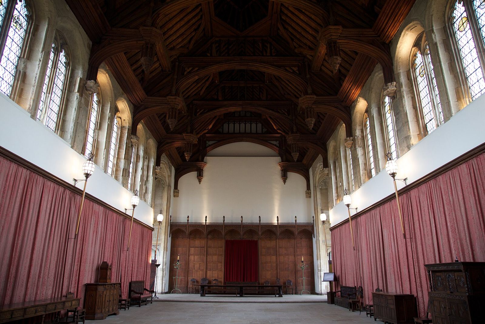 Interior of a medieval great hall with a hammerbeam roof and stained-glass windows